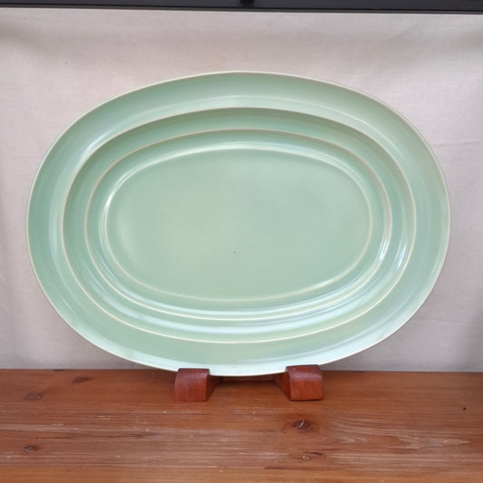 Green ceramic plate on a wooden surface with a neutral background