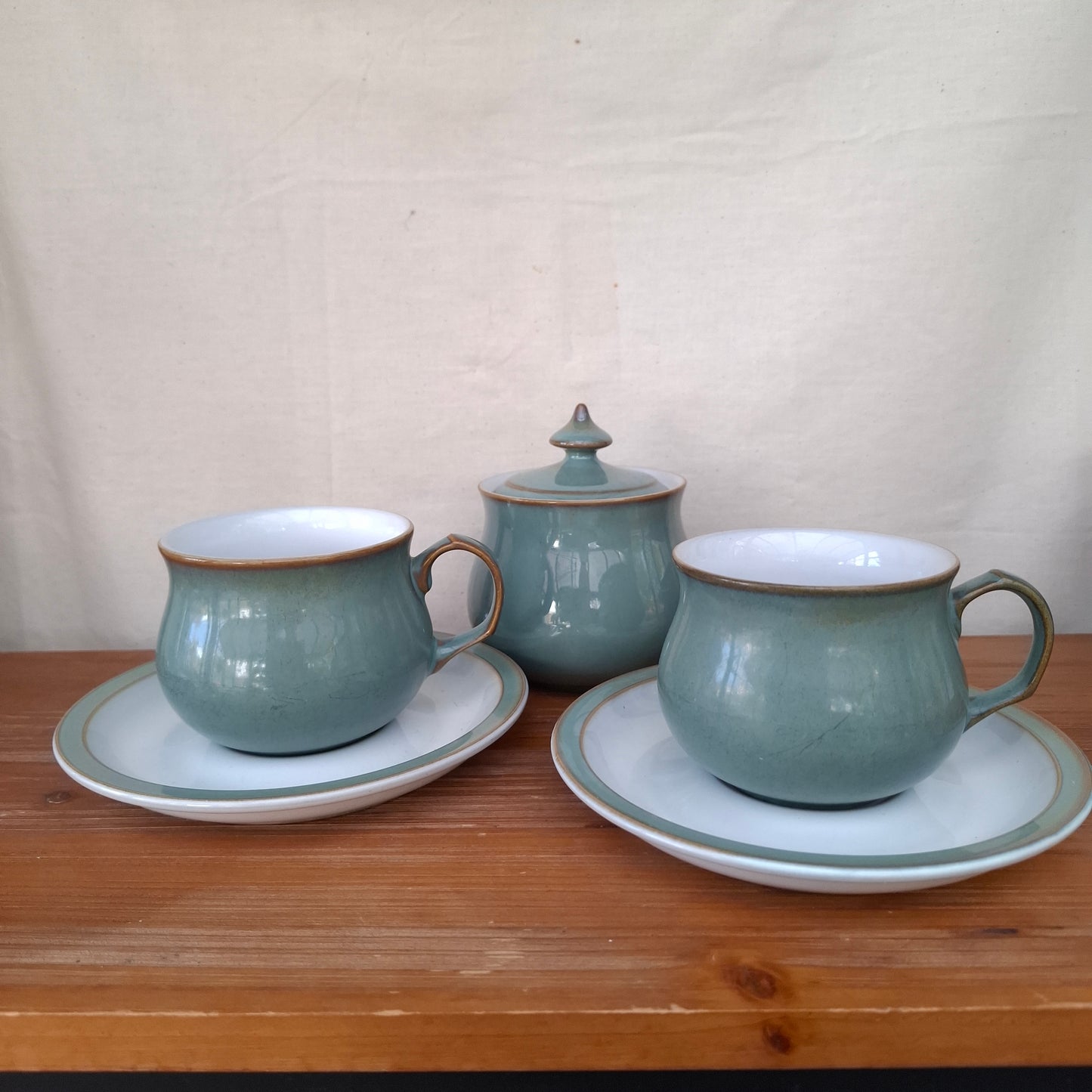 Two ceramic teacups with saucers on a wooden surface.