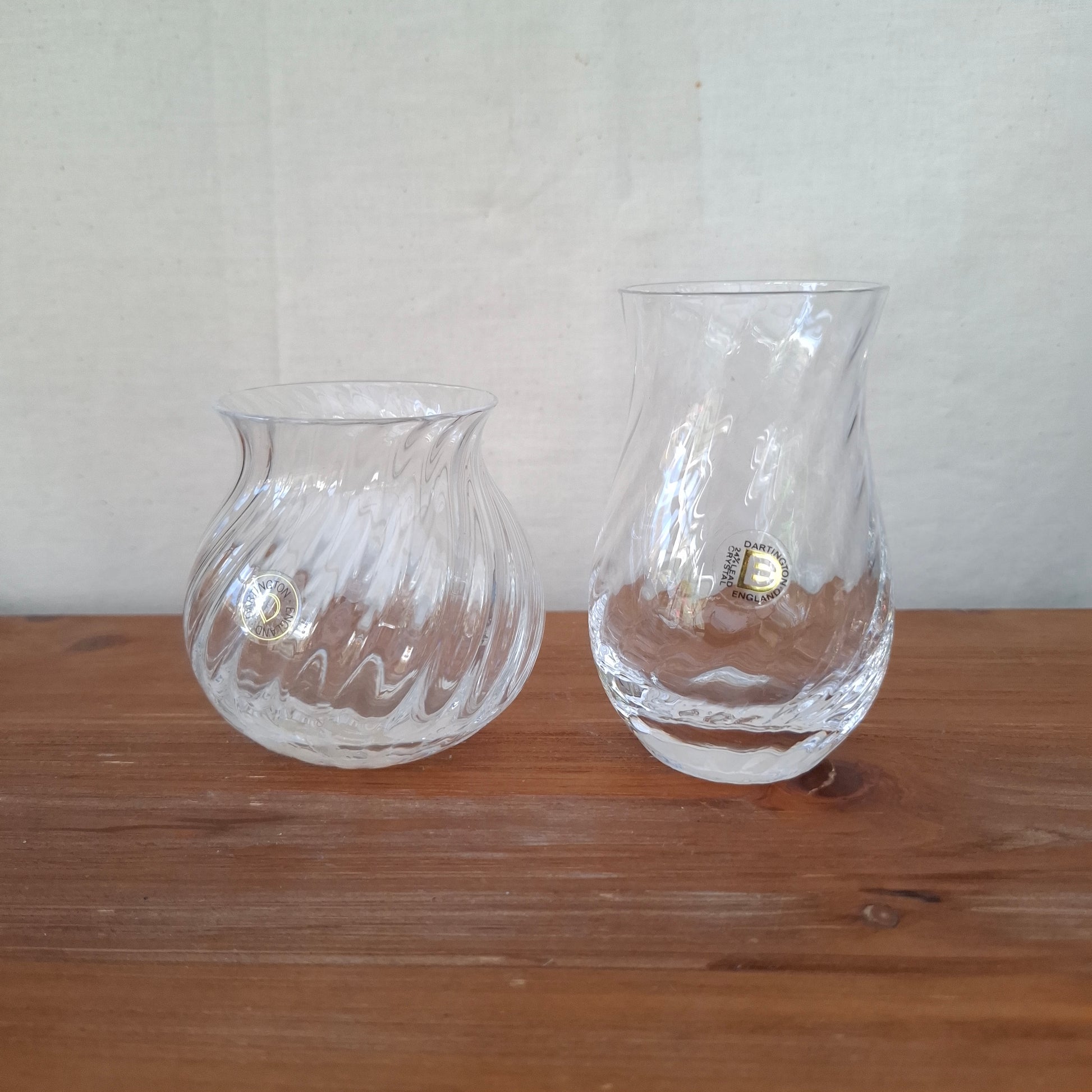Two clear glass wall sconces on a wooden surface.