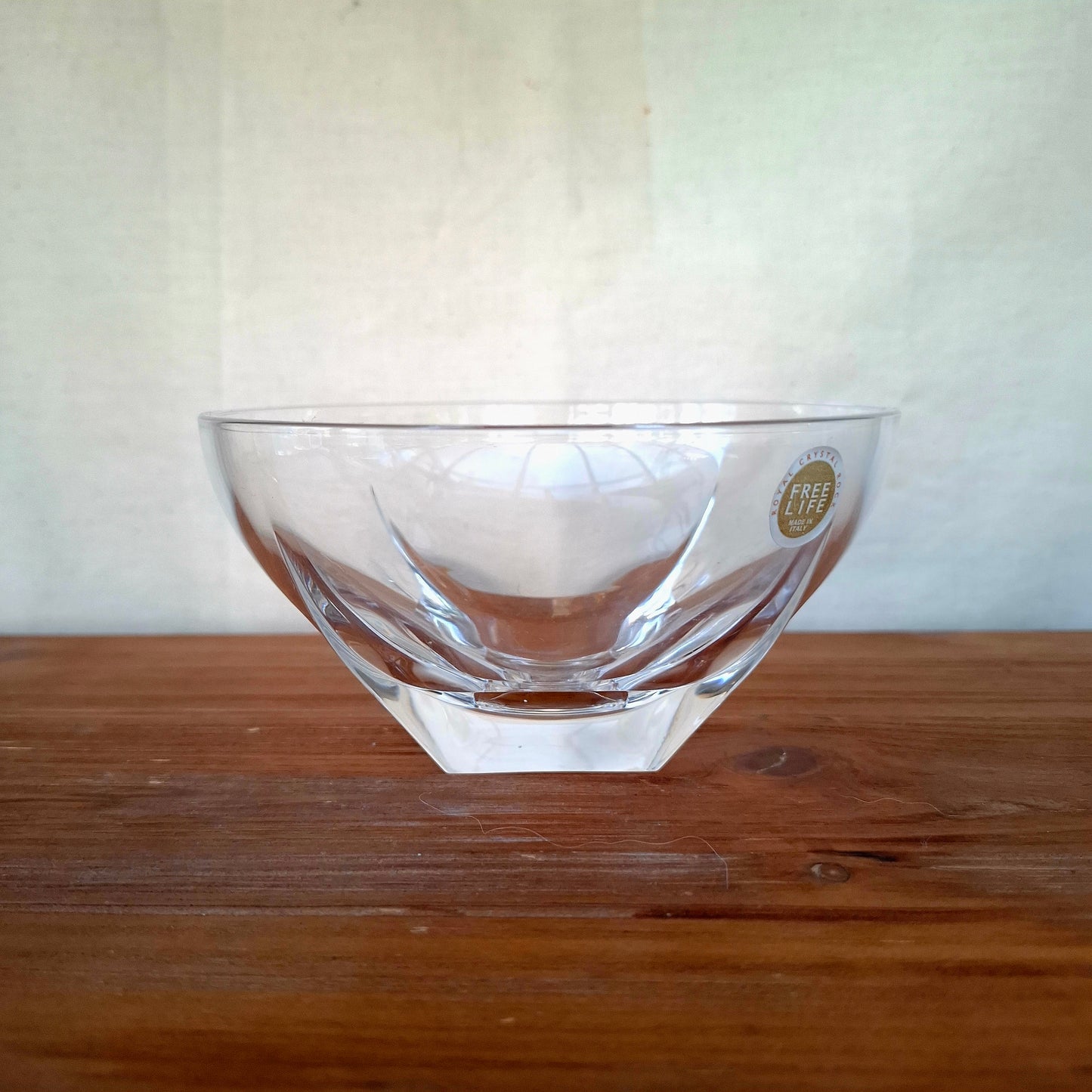 Clear glass bowl with a logo on a wooden surface and white background