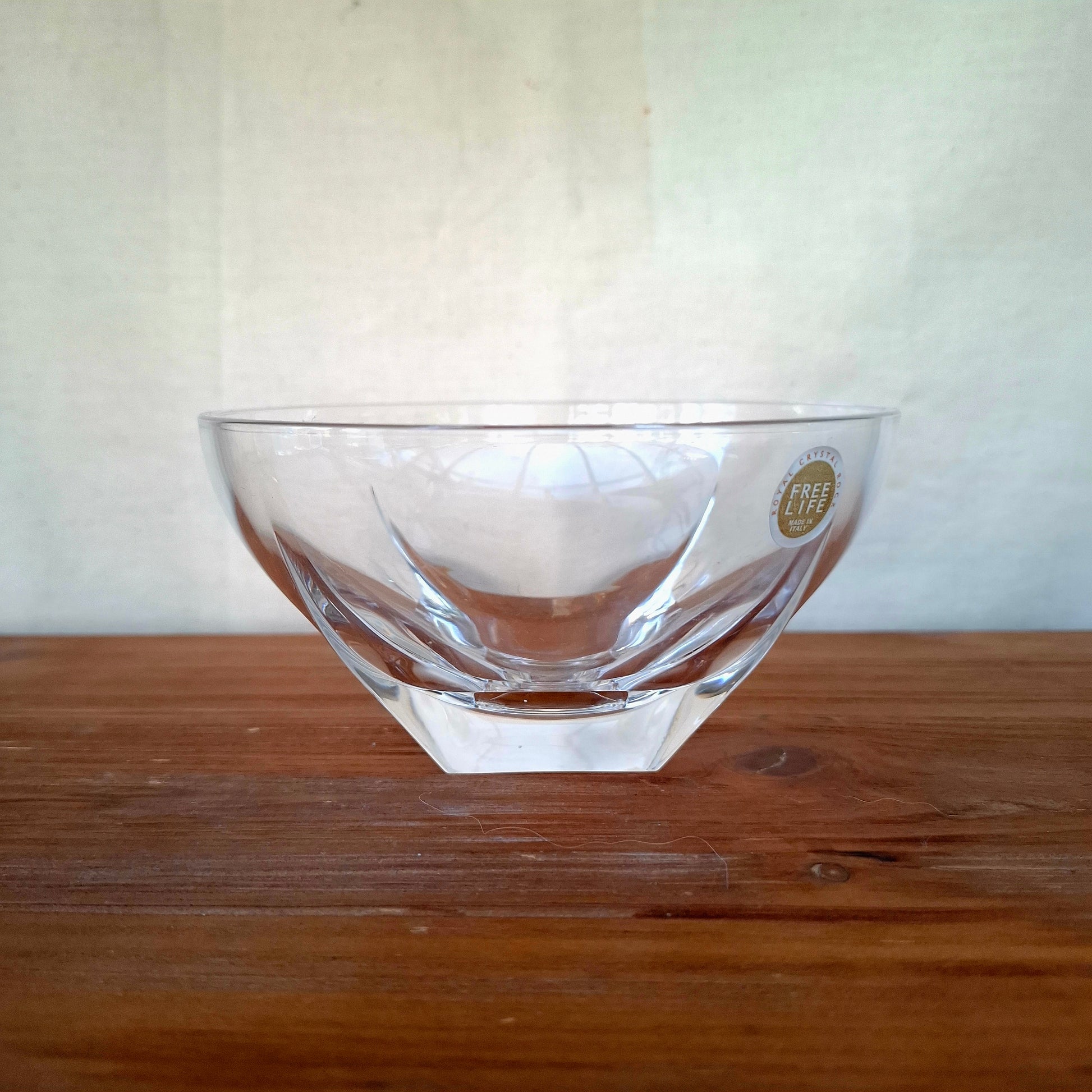 Clear glass bowl with a logo on a wooden surface and white background
