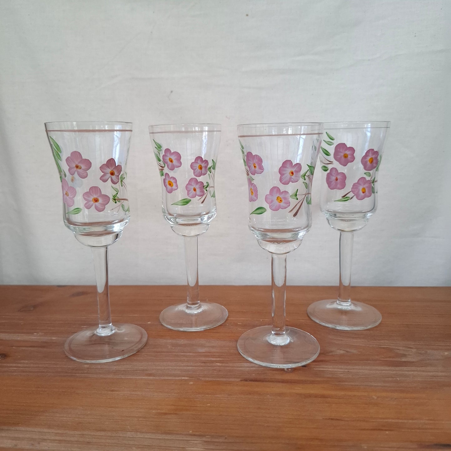 Set of four floral-patterned wine glasses on a wooden surface.