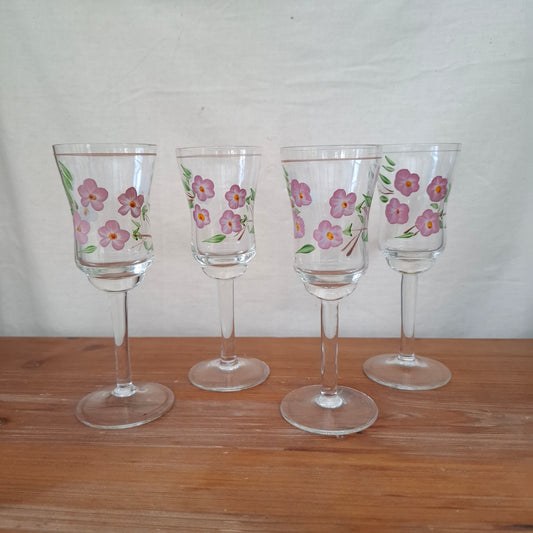 Set of four floral-patterned wine glasses on a wooden surface.